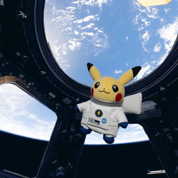 Űrhajósruhás Pikachu plüssfigura a Nemzetközi Űrállomás Cupola ablakában, mögötte a Föld
